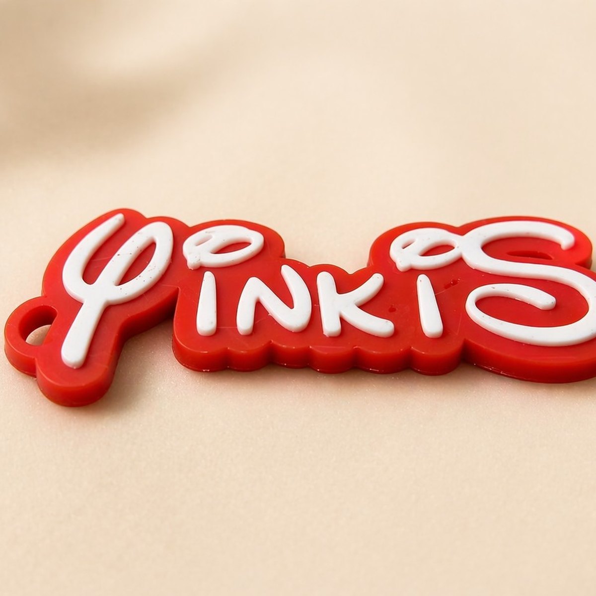 Llavero 3D personalizado con la palabra Yinkis en cursivo blanco sobre acrílico rojo