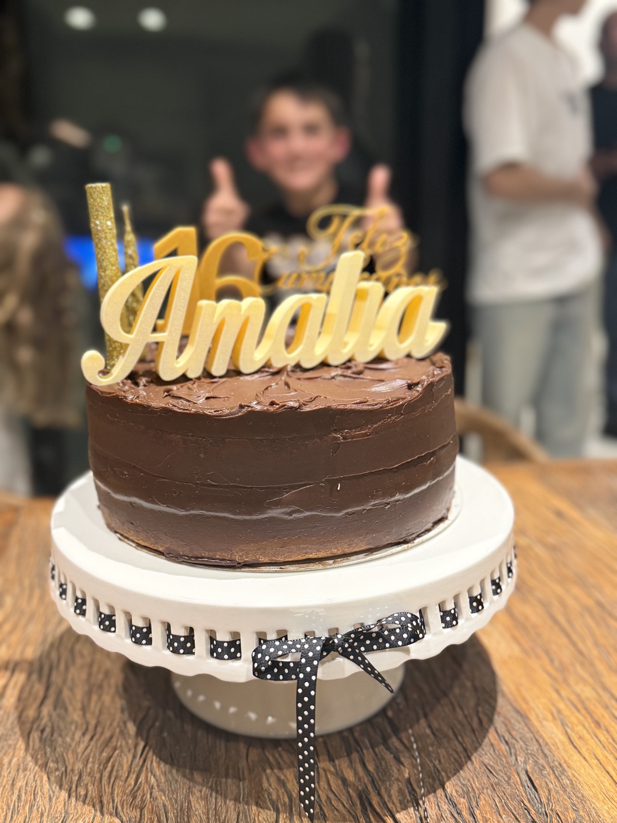 Cake topper Feliz Cumpleaños Amalia 16 dorado, sobre torta de chocolate, momento real del evento